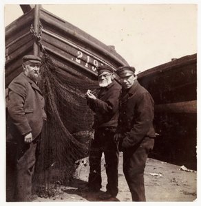 Fishermen standing by a net, c 1905