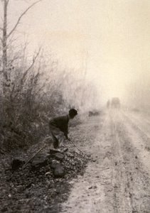 A Country Road Wrapped in Morning Mists with a Man Splitting Stones in the Foreground