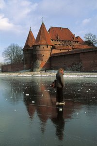 Side profile of a man standing on a frozen river in front of a castle, Nogat River, Malbork Castle, Malbork, Pomorskie Province, Poland