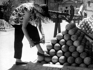 A woman adjusts the cuff of her pants as she rests her foot on a pile of cannonballs inside the grounds of Castel Sant