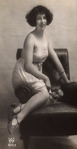 A young woman posing in her petticoat, sitting in an armchair by Unknown photographer