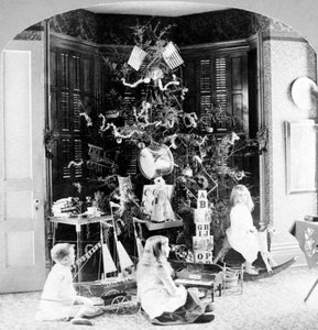 Children gathered at the foot of the tree surrounded by gifts on Christmas morning by Unknown photographer