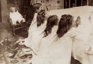 Four little girls kneeling at the side of a bed as they say their evening prayer by Unknown photographer