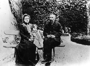 Pierre (1859-1906) and Marie Curie (1867-1934) sitting on a bench in a garden
