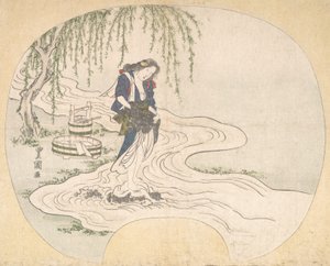 A Woman Stands on a Rock in a Stream Washing Clothes