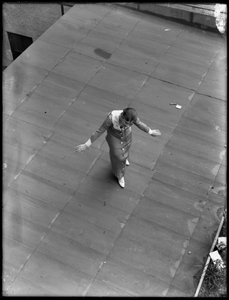 Girl stenographer on roof with arms spread as if taking a bow, August 22, 1914