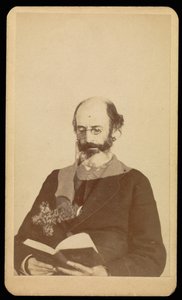 Unidentified balding, bearded man reading while seated
