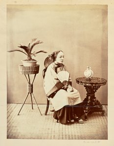 Studio Portrait of a Seated Young Woman Holding a Fan