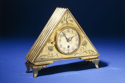 A Triangular Brass Table Clock with Engraved Floral Decoration by Dagobert (attr. to) Peche