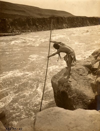 Tlakluit Indian, standing on rock, fishing with dip net by Edward Sheriff Curtis