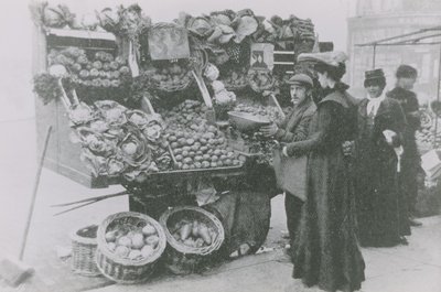 A Grocer Serving a Woman Beside His Stall by English Photographer