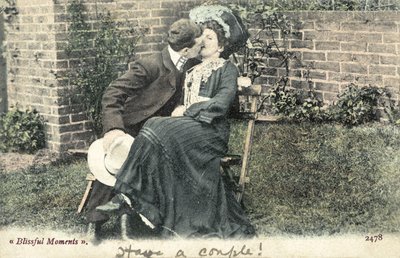 Man grabbing a kiss from a girl on a garden bench by English Photographer