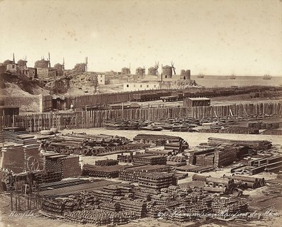 Yard for construction materials, windmills are in the background, in Alexandria, Egypt by Félix Bonfils