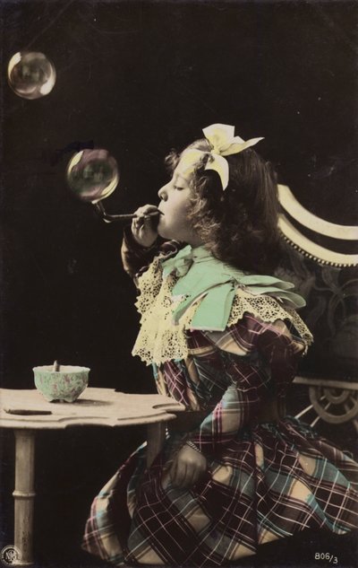 A little girl blowing bubbles from a pipe by French Photographer