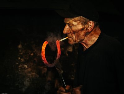 Blacksmith Lights Cigarette by Maciej Przeklasa