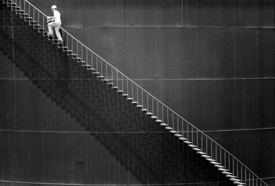 Man climbs steps on side of an oil storage tank by Ted Spiegel