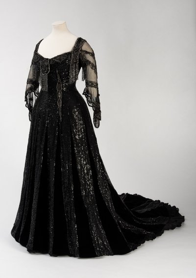 Black full length evening gown worn by Queen Alexandra, with bead and sequin decoration and incorporating Queen Alexandra’s signature black silk and gold lettered name tape, made by Barolet of Knightsbridge, London 1908-1910 by Unbekannt