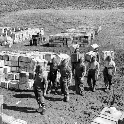 A Compo Ration Dump and Men Carrying More Supplies to It, March 1943 by Unbekannt