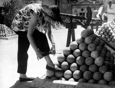 A woman adjusts the cuff of her pants as she rests her foot on a pile of cannonballs inside the grounds of Castel Sant