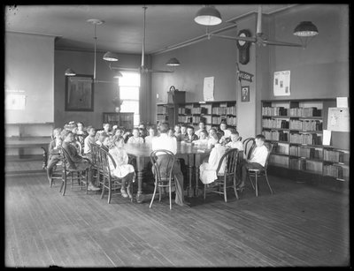 Children Listen to a Woman in the Reading Room of an Unidentified Branch of the Queens Borough Public Library, c.1910 by William Davis Hassler