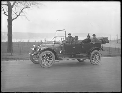 Three unidentified people and two Chow dogs driving in a convertible car along a river or lake by William Davis Hassler