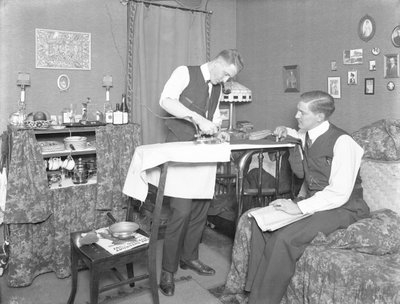 Unidentified Man Demonstrating the Use of an Electric Iron, Watched by Another Man, c.1913-14 by William Davis Hassler