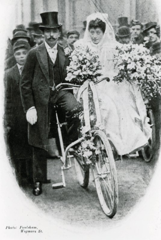 Roman Catholic couple leaving Notre Dame de France, Leicester Square, on bicycles by English Photographer