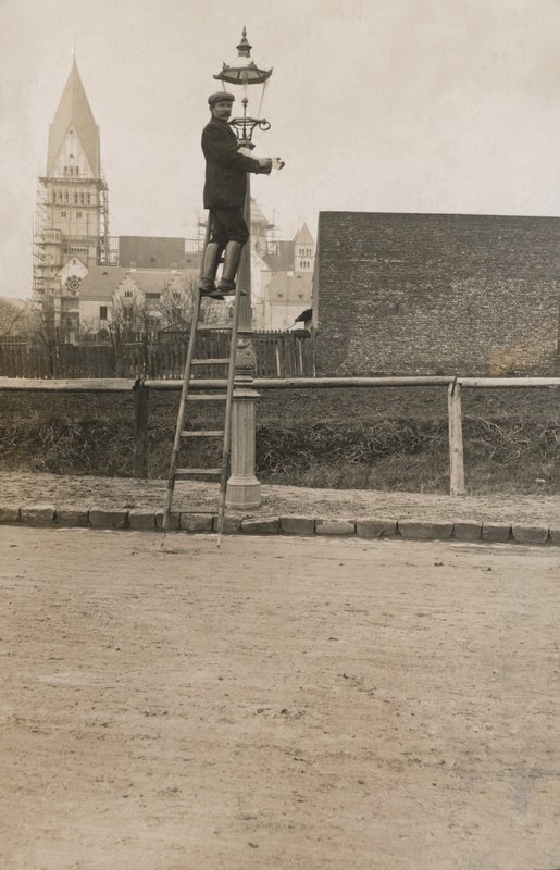 Man up a ladder fixing a street lamp by European Photographer