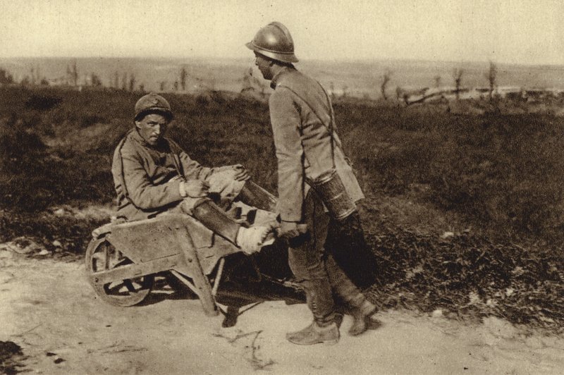 Captured French soldier transporting his wounded comrade in a wheelbarrow, World War I by Photographer German