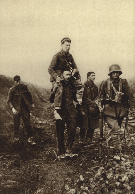 German infantryman with a leg wound being carried from the battlefield by British prisoners, World War I by Photographer German
