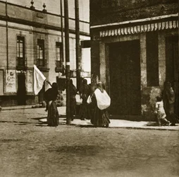 Women walking in the streets under the cover of a white flag during 