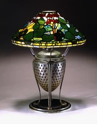 A "Geranium" table lamp with a conical shade, and reticulated bronze urn base with a fishscale pattern, 20th century
