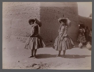 Two women carrying clay jugs