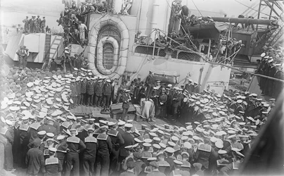 Seamen crowd around Australian Prime Minister William Morris (Billy) Hughes as he addresses them on the deck of HMAS Australia at the dockyard in Devon, England, 21 May 1916