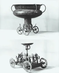 Two votive chariots for collecting rainwater: Top - cup supported on four wheels from the Peccatel tumulus, Mecklembourg, Germany. Bottom - standing female divinity beneath a plate surrounded by warriors