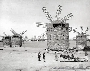 Windmills on the Mediterranean Sea in Alexandria, Egypt. In front, some Egyptians posing with a small cart