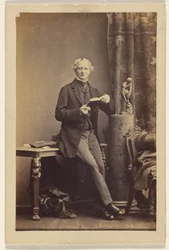 Unidentified Man Seated on Table, Holding an Opened Book