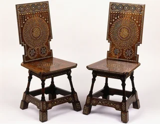 A pair of mahogany chairs with pewter and ivory inlaid floral decoration