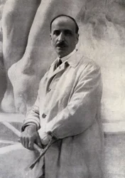 Three-quarter-length portrait of the sculptor Edoardo Rubino with marteline in hand. In the background a sculpture can be made out
