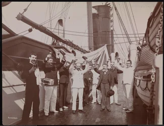 Officers and crew toasting with champagne and cigars on the deck of the S.S. Umbria, c.1897