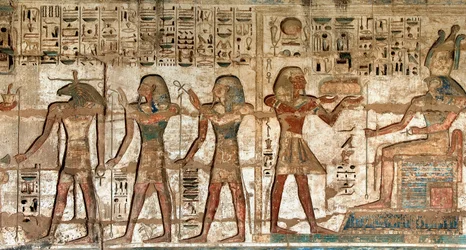 First court, detail of painted reliefs depicting the pharaoh carrying offerings to the deities Horus and Khnoum. Funeral Temple of Ramses III, Luxor, Medinet Habou, Egypt