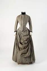 Grey cotton dress with draped apron front and black velvet trimming at collar and cuffs, late 1880s