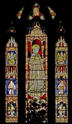 The East window depicting musician angels surrounding the central figure of a sainted bishop