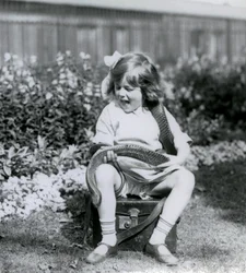A young girl Betty holding an Eastern Indigo Snake, while sitting on a leather trunk, London Zoo, 1924