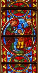 Window w213 depicting a scene from the life of St Thomas: the saint at a marriage banquet for the daughter of the king of India has his face slapped by a cupbearer; a lion removes his arm