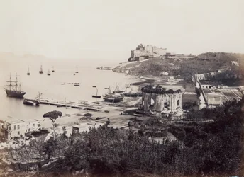 Panorama of the picturesque Gulf of Baia, dotted with sailboats. In the foreground, opposite the small wharf, is the Temple of Venus. In the background, perched on a promontory, is the Sixteenth century Castle of the Viceroy