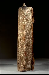 Curved rectangular Sepik shield, the front with central band of five masks, each with fibre in the pierced septum, within panel of carved zigzags