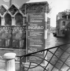 View of a canal in Venice with posters advertising a Giorgione exhibition and a political manifesto in foreground