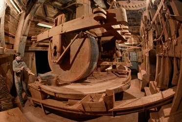 A man grinds cacao bean shells for animal feed in a 100-year-old mill, Ooievaar Mill