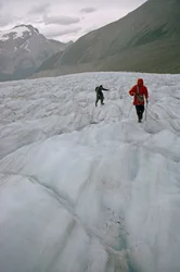 Two tethered mountain climbers on a glacier approach a crevasse